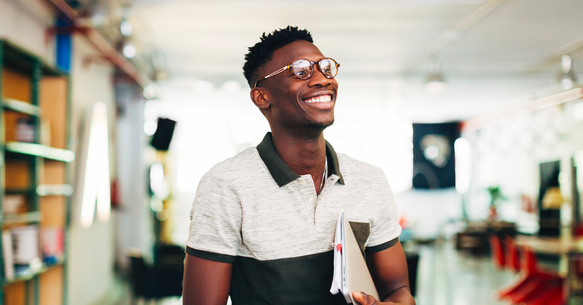 A smiling person holding documents, showing the process of putting together a financing plan for a business.