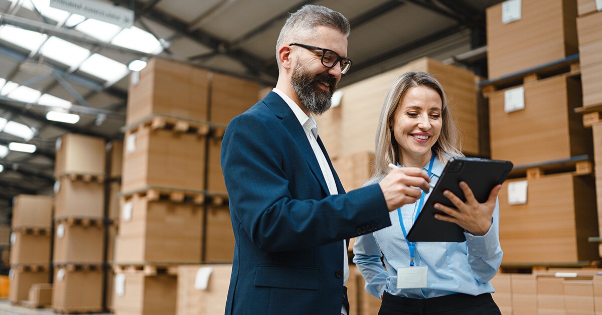 Two people looking at a tablet in a warehouse as they plan their international business expansion. 