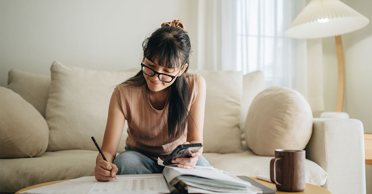 A person calculating her budget and writing in a notebook
