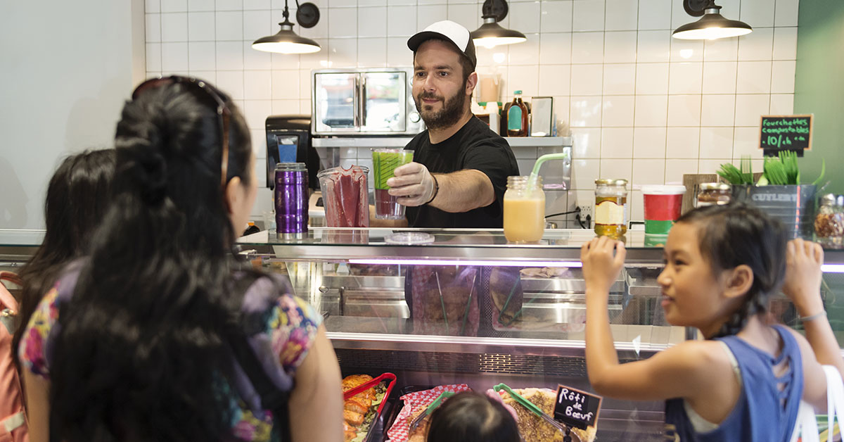 Propriétaire d'une petite entreprise offrant un verre de jus de fruits à des clients.